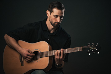 A man playing and looking at his guitar